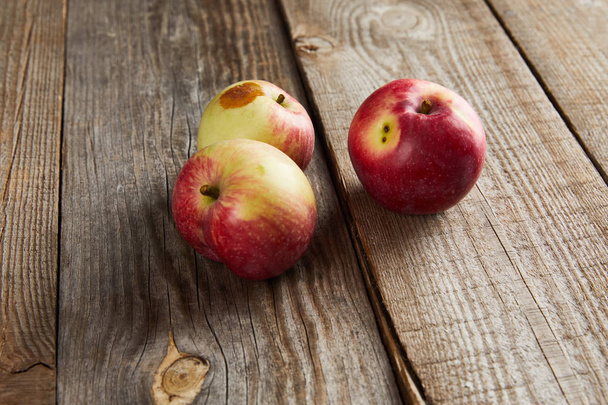 appels met rotte vlek op bruin houten oppervlak - Foto, afbeelding