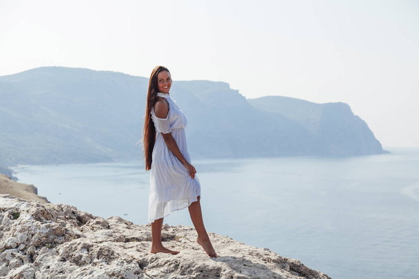 gyönyörű nő hosszú hajjal egy sziklán óceán - Fotó, kép