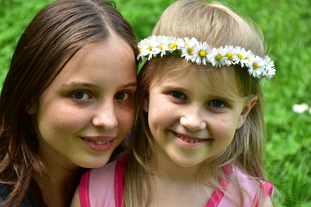 πορτρέτο δύο κοριτσιών με ένα στεφάνι από μαργαρίτες στο κεφάλι τους, - Φωτογραφία, εικόνα