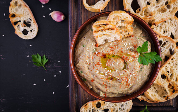 Baba ghanoush vegan hummus from eggplant with seasoning, parsley and toasts. Baba ganoush. Middle Eastern cuisine. Top view, overhead - 写真・画像