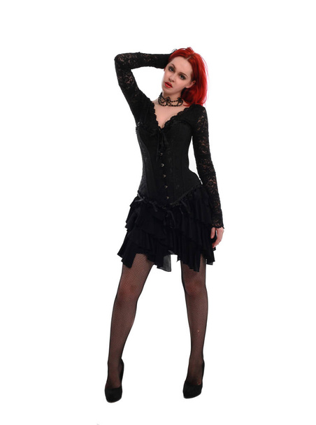 Pełna długość Portret czerwonej włosach dziewczyna ubrana w czarną gotycką suknię, stojący Pose na szarym tle studyjnej. - Zdjęcie, obraz