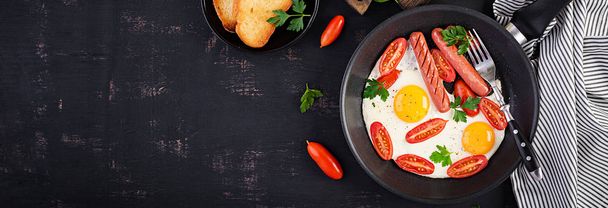 Desayuno inglés: huevo frito, tomates, salchichas y tostadas
.  - Foto, Imagen