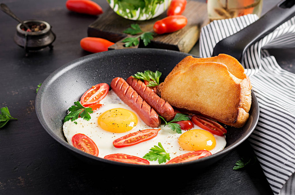 Desayuno inglés: huevo frito, tomates, salchichas y tostadas. Vista superior
 - Foto, Imagen