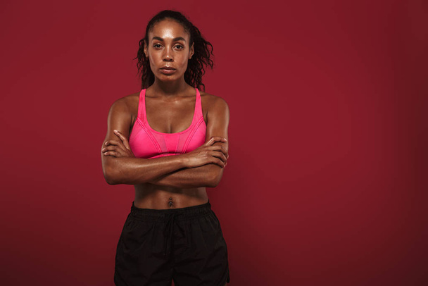 Strong young african fitness sports woman posing isolated over red wall background. - Photo, Image