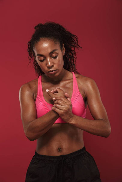 Strong young african fitness woman posing isolated over red wall background. - Foto, imagen