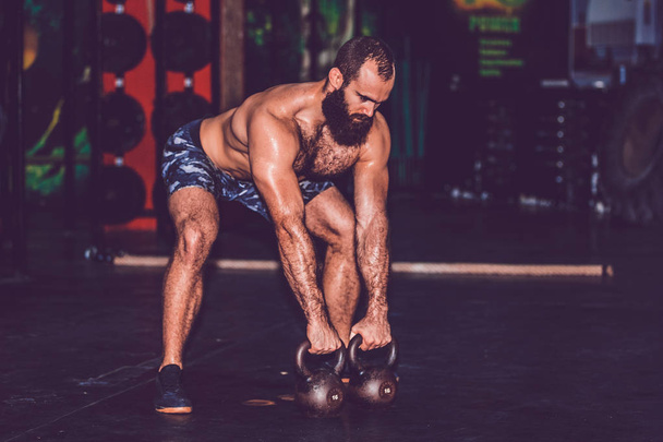 Young bearded man using kettlebell in his workout at the gym - Fotó, kép