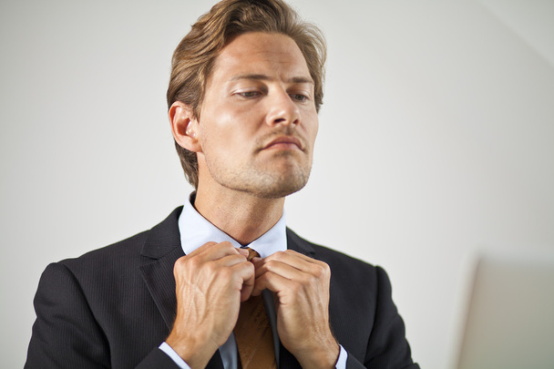 Serious businessman adjusting tie - Фото, зображення