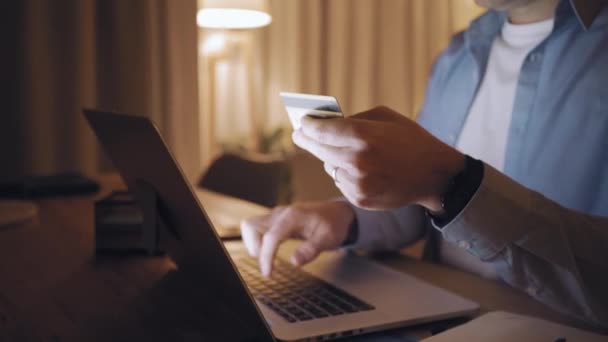 A man shopping online on laptop using credit card at late night - Felvétel, videó