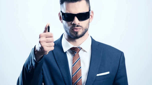 Geschäftsmann in Anzug und Sonnenbrille mit Stift auf weißem Hintergrund  - Filmmaterial, Video
