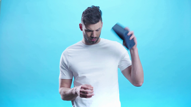 rozčilený muž držící prázdnou peněženku na modrém  - Záběry, video