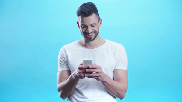 positive man using smartphone on blue  - Materiał filmowy, wideo