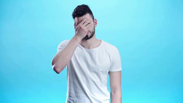 незадоволений чоловік прикриває обличчя на синьому
  - Кадри, відео