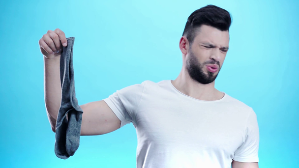 man holding smelly socks on blue  - Video, Çekim