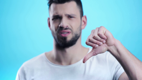 upset man showing thumb down on blue  - Metraje, vídeo
