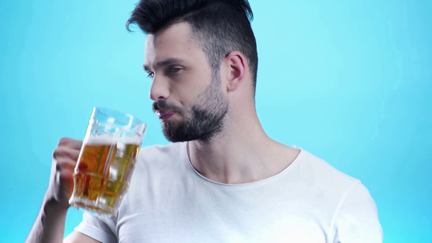 schöner Mann, der Bier auf blau trinkt  - Filmmaterial, Video