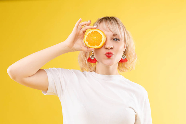 Śmieszne modne dziewczyny z fryzurą trzymając pomarańcze na oczach. - Zdjęcie, obraz
