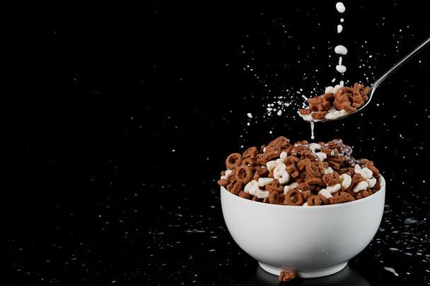 tigela branca com cereal sortido e colher com gotas de leite isoladas em preto
 - Foto, Imagem