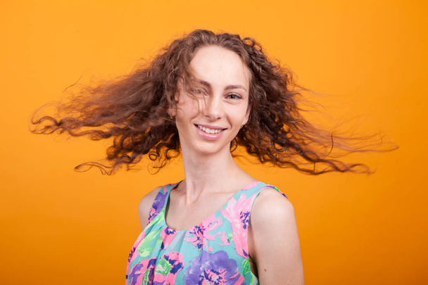 Pompás kaukázusi womam rázta a haját mint narancssárga háttér - Fotó, kép