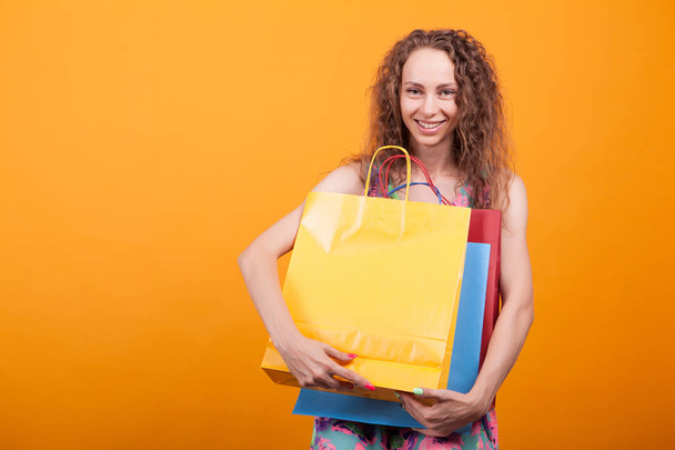 Örömteli fiatal hölgy mosolyogva bevásárló táskák a kezében - Fotó, kép