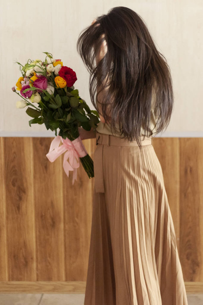 Beautiful middle-eastern girl with a bouquet of flowers in hands. Young attractive female with flowers. Portrait of charming, pretty girl holding flowers bouquet - Foto, Bild