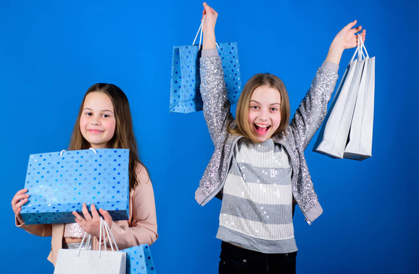 Small girls with shopping bags. Sisterhood family. savings on purchases. Kid fashion. Blue backdrop. Sales discounts. Happy children. Little girl sisters. Small girls with pack. Small girls in mall - Zdjęcie, obraz