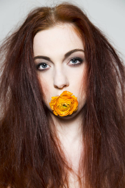 Disheveled redhead girl holds rose in her mouth - Fotoğraf, Görsel