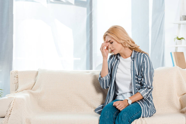 upset woman with closed eyes sitting on sofa  - Φωτογραφία, εικόνα