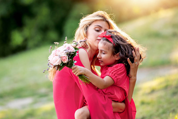 Happy mom and daughter smiling in summer park. - 写真・画像