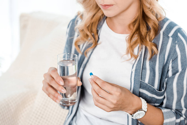 cropped view of woman holding glass with water and pill  - Photo, Image