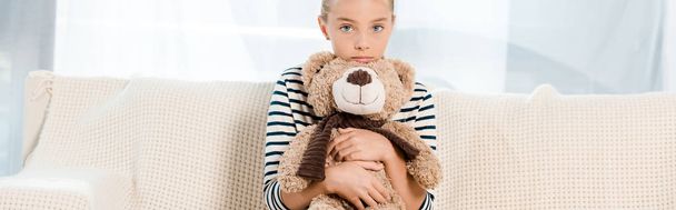 panoramic shot of kid holding teddy bear in living room  - Foto, Bild