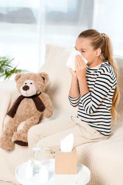 sick kid sneezing in tissue neat teddy bear  - Fotografie, Obrázek