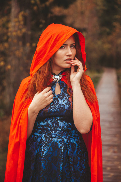 Mooie rode Riding Hood vrouw gaat op Autumn Forest Road. - Foto, afbeelding