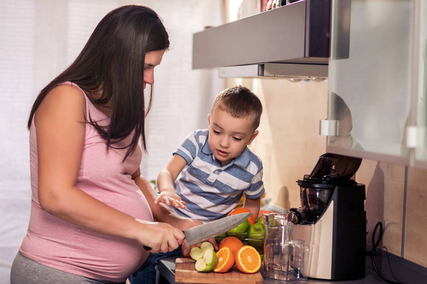 Familie stellt frischen Orangensaft in der Küche her und genießt die gemeinsame Zeit. - Foto, Bild