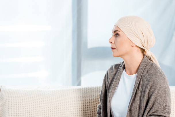 sad and sick woman with head scarf in living room  - Photo, Image