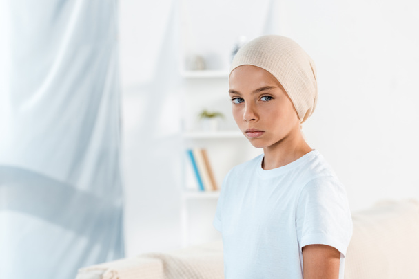 sick kid in head scarf looking at camera at home  - Photo, Image