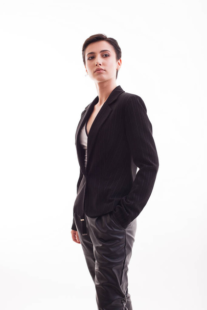 Charming young woman in a stylish black jacket in studio over white background - 写真・画像