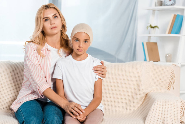 sad mother sitting on sofa with sick daughter  - Photo, Image