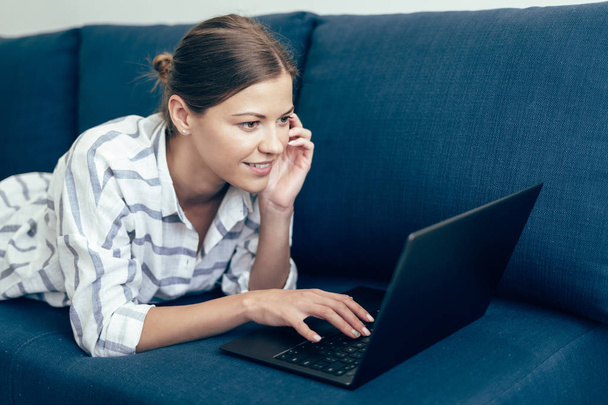 Giovane donna adulta sdraiata sul divano, utilizzando il computer portatile
 - Foto, immagini