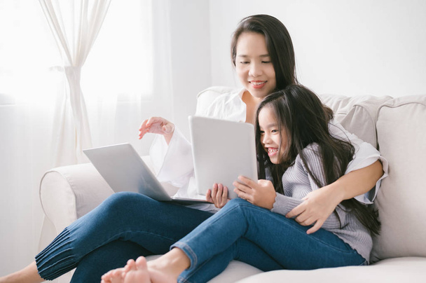 feliz madre e hija con ordenador portátil y tableta PC
 - Foto, imagen