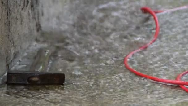 Hammer und rotes Kabel auf einer Baustelle bei starkem Regen - Filmmaterial, Video