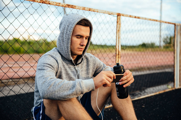 Sportsman using mobile phone with bottle of water - Fotoğraf, Görsel