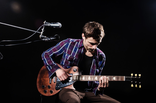 Mies soittaa kitaraa konsertin aikana
 - Valokuva, kuva