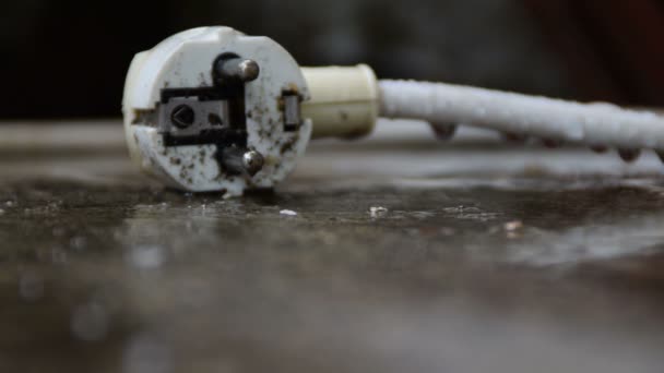 Witte plug liggend op de grond tijdens een regen  - Video