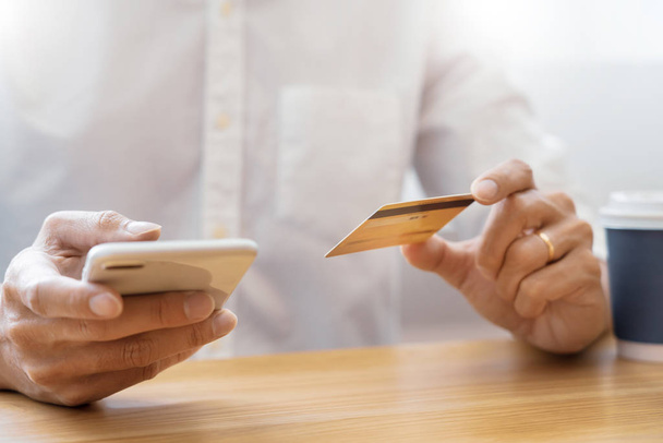 Mano del hombre en camisa casual pagando con tarjeta de crédito y usando sm
 - Foto, imagen