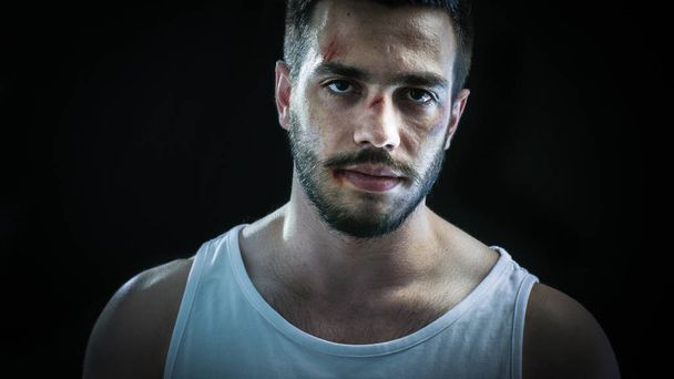 Aggressive Man with a Bruised Face Wearing Singlet Standing and Aggressively Looks into the Camera. Background is Isolated Black. - Zdjęcie, obraz