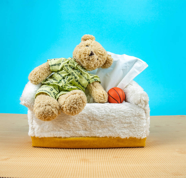 Teddy Bear indossa il pigiama e sedersi sulla scatola di tessuto con baske
 - Foto, immagini