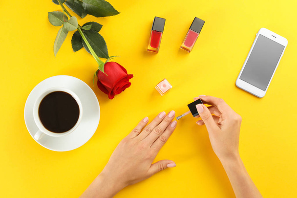 Woman applying nail polish on color background, top view - Photo, image