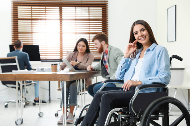 Young woman in wheelchair with colleagues at office - Foto, Imagem