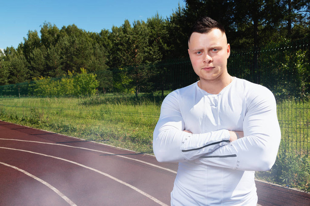 fitness, sport, exercising and lifestyle concept - athlete stands at the sports stadium and looks at the camera. - Zdjęcie, obraz