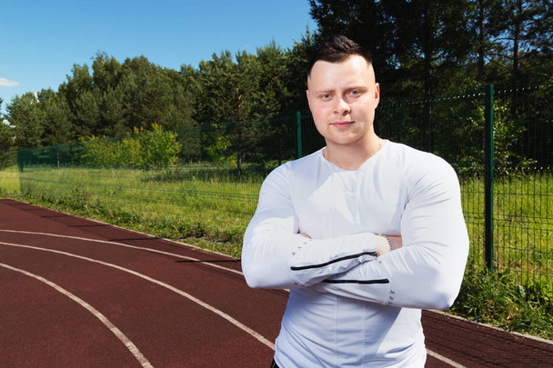 fitness, sport, exercising and lifestyle concept - athlete stands at the sports stadium and looks at the camera. - Fotografie, Obrázek
